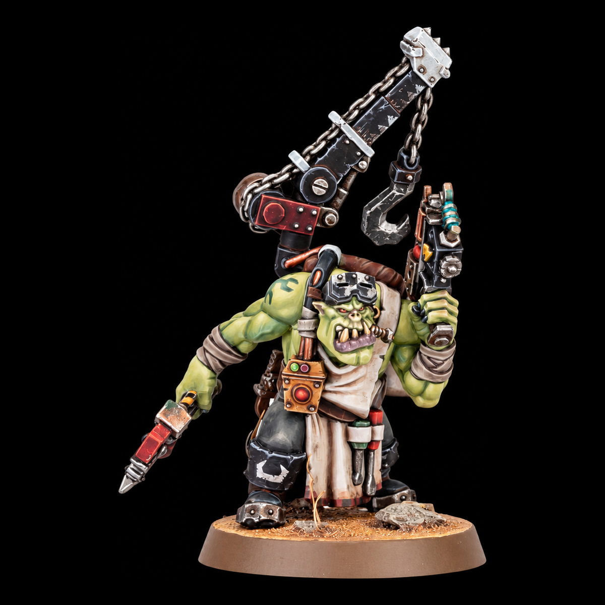 Miniatura Ork Mek de Warhammer, con grúa, gancho, pistola y herramientas, vista frontal sobre peana.