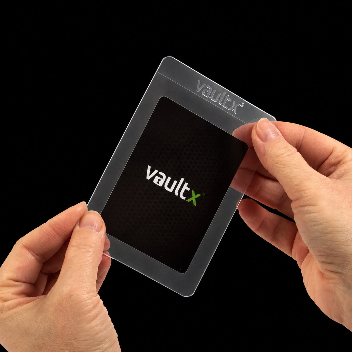 Manos introduciendo una carta de muestra en una funda semirrígida transparente Vault X.