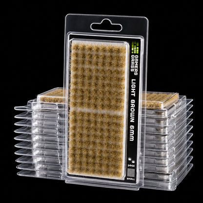 Blíster Light Brown 6 mm Small de Gamer’s Grass con pequeñas matas marrón claro y envases apilados.