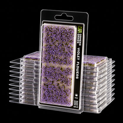 Blíster Violet Flowers de Gamer’s Grass con pequeñas flores violetas y envases apilados detrás.