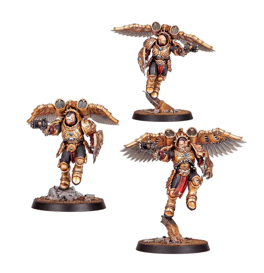 Tres miniaturas aladas de Adeptus Custodes Combat Patrol de Warhammer, con armaduras doradas, armas y escudos sobre peanas.